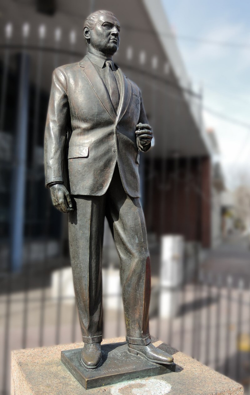 Escultura de bronce de Julio Sosa rodeada de vegetación, frente a la Plaza Artigas en Las Piedras, Uruguay