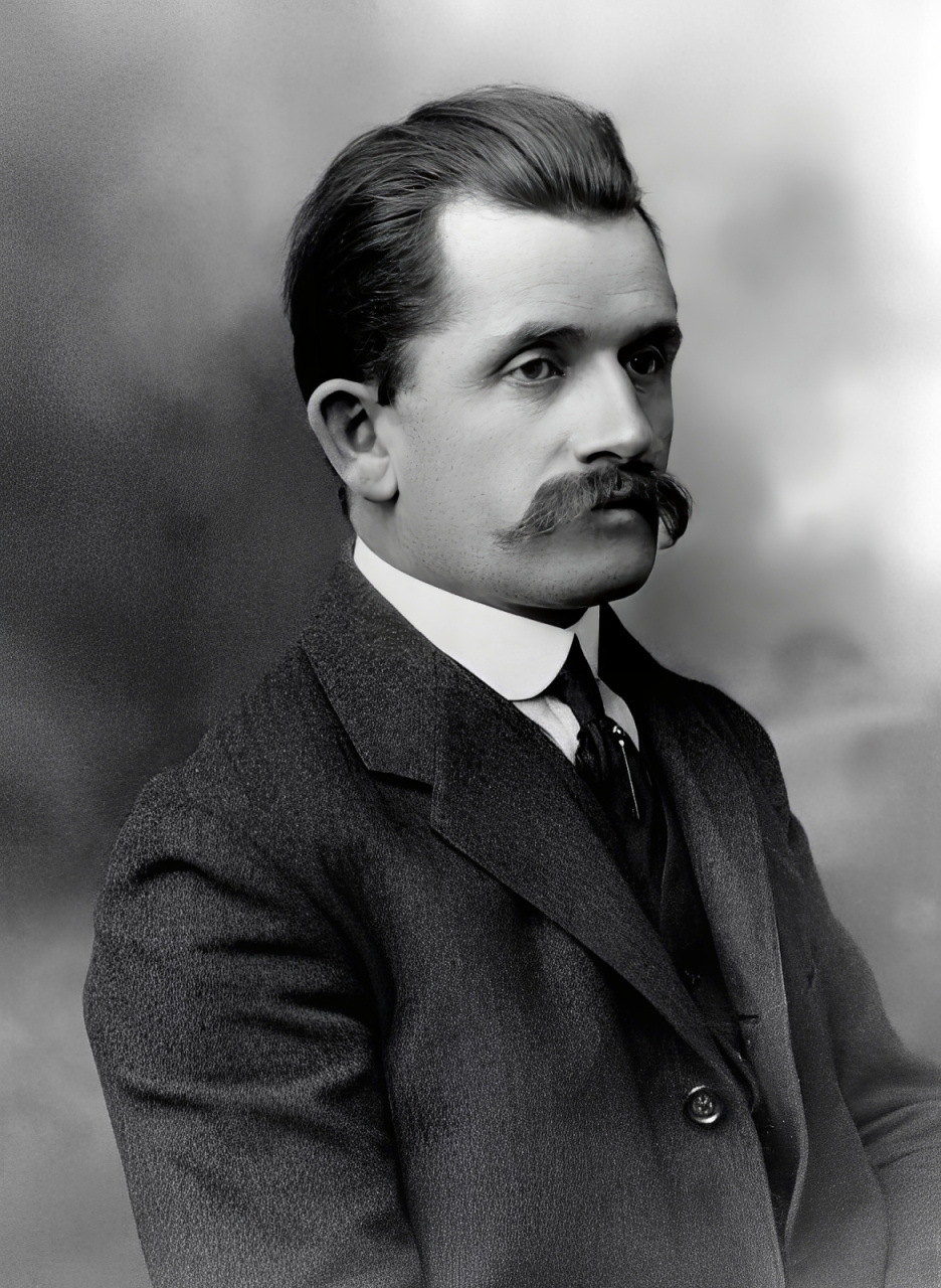 Retrato de Ferdinand Porsche, ca. 1905: busto de tres cuartos, joven, con bigote prominente y traje oscuro.