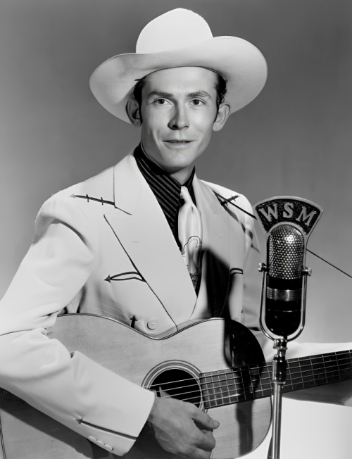 Hank Williams in a white suit and cowboy hat, posing with a guitar in front of a WSM radio microphone