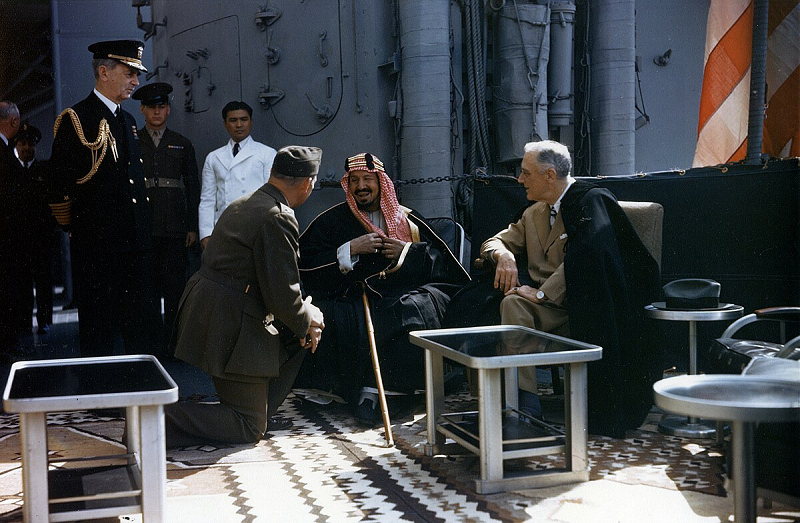 King Ibn Saud and U.S. President Franklin D. Roosevelt aboard the USS Quincy in 1945, seated on ornate rugs with military officers nearby